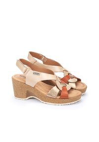 Sandalias de cuña con suela de corcho, hechas de cuero dorado y marrón claro, con correas en el tobillo ajustables y acentos decorativos tejidos en naranja y beige.