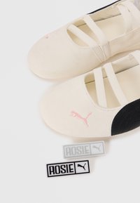 Baleríny s béžovým semišovým vrškom a čiernymi koženými detailmi, s ružovým logom Puma a elastickými pásikmi. Súčasťou sú aj dva štítky "ROSIE".