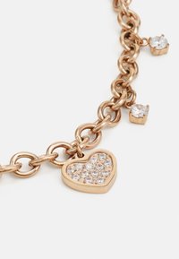 Bracelet en chaîne en or rose avec un charme en forme de cœur, serti de strass clairs et de deux petites pierres claires supplémentaires.