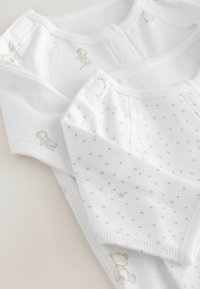 To hvide baby bodyer med tryknapper, en med små grønne prikker og stjerner, den anden med små dyreillustrationer.