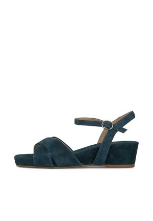 Tmavě modrá semišová klínová sandála s překříženými pásky, otevřenou špičkou a nastavitelným páskem kolem kotníku se stříbrnou přezkou.