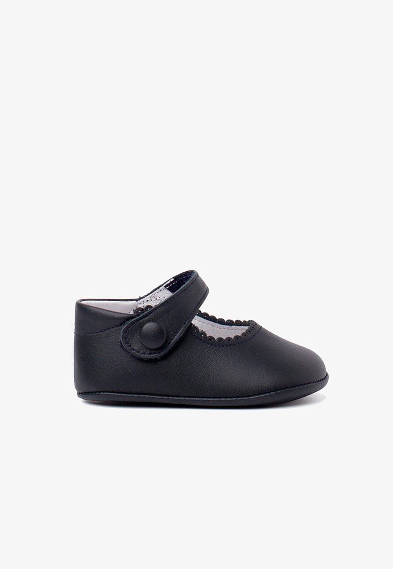 Scarpina per bambini in pelle nera con punta arrotondata, bordi scallopati e una cinturino con bottone arrotondato. Soletta morbida per comfort e flessibilità.