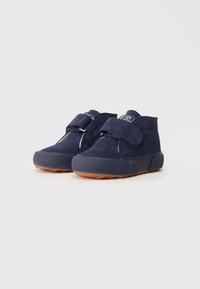 Scarpe in suede blu navy con cinturino in Velcro, punta arrotondata, suola in gomma e motivo testurizzato sulla suola esterna. Altezza alla caviglia sopra il piede.