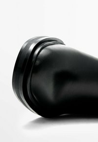Botte en cuir noir avec un bout arrondi et une surface lisse, dotée d'une bande noire élégante en haut pour plus de détail et de renfort.