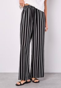 Black and white striped wide-leg pants with an elastic waistband, featuring a smooth texture and a full-length design.
