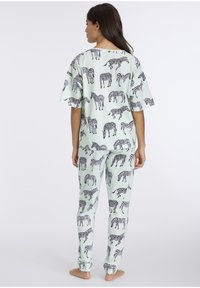 Mintgrünes Schlafanzugset mit einem kurzärmeligen Oberteil und passender Hose, beide mit einem schwarzen Zebramuster verziert. Weicher Stoff, lockere Passform.