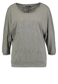 Locker sitzendes, graues T-Shirt mit weitem Ausschnitt. Mit einem silbernen Strass-Palmbaumdesign auf der Vorderseite. Strukturierter Stoff, 3/4-Ärmel.