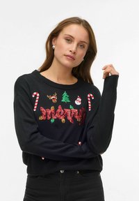 Juodas megztinis su šventiniais papuošimais: siūtu žodžiu „Merry“, saldainių lazdelių, elnio, eglutės ir sniego senio piešiniais. Ilgos rankovės.