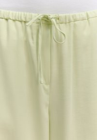 Lichtgroene, lichte stoffen broek met een elastische tailleband en trekkoord. Glad textuur, eenvoudig ontwerp en geen zichtbare patronen.