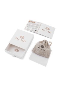Cutie albă cu logo roz auriu, însoțită de un săculeț din in cu șnur și o cârpă de curățare. Include un card de mulțumire cu instrucțiuni de întreținere.