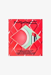 Packaging di un prodotto MAC con un design geometrico rosso e un ritaglio che rivela un blush morbido rosa e un balsamo labbra rosso.