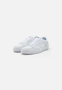 Sneakers bianchi realizzati in pelle e materiali sintetici, con un design a profilo basso, punta perforata e accenti texturizzati.