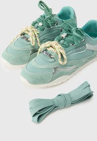 Πράσινα αθλητικά παπούτσια σε απόχρωση μέντας με υλικά σουέτ και διχτυωτά. Διαθέτουν λαμπερά  στοιχεία και χαρακτηριστικά κορδόνια. Περιλαμβάνουν επιπλέον ένα επιπλέον κορδόνι στο ίδιο χρώμα.