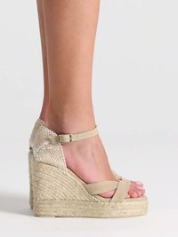 Sandales compensées beiges avec plateforme en corde tressée et bride de cheville attachée à un pied sur un fond uni clair.