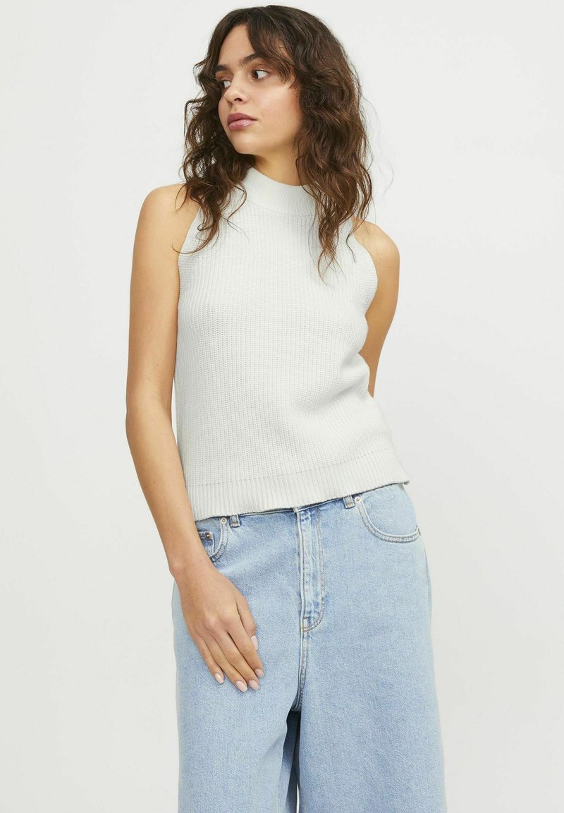 Top senza maniche a coste grigio chiaro con un collo alto; abbinato a jeans a gamba larga in denim blu chiaro; texture liscia e design aderente.