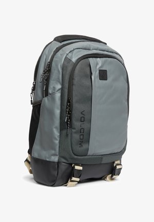Grauer und schwarzer Volcom Rucksack mit mehreren Reißverschlussfächern und beigen, verstellbaren Trägern am unteren Teil.