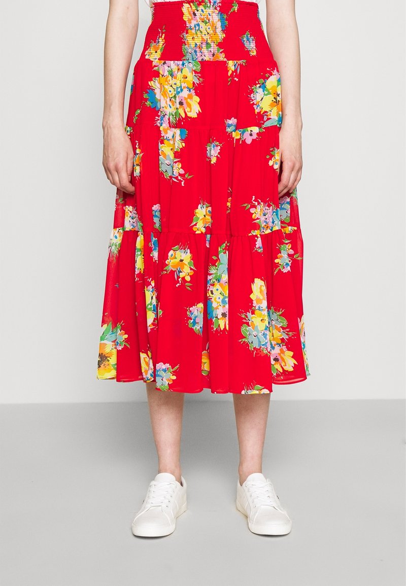 Roter Midi-Rock mit Blumenmuster und gesmoktem Bund; leichtes Material, gestuftes Design mit bunten Blumen; kombiniert mit weißen Sneakern.