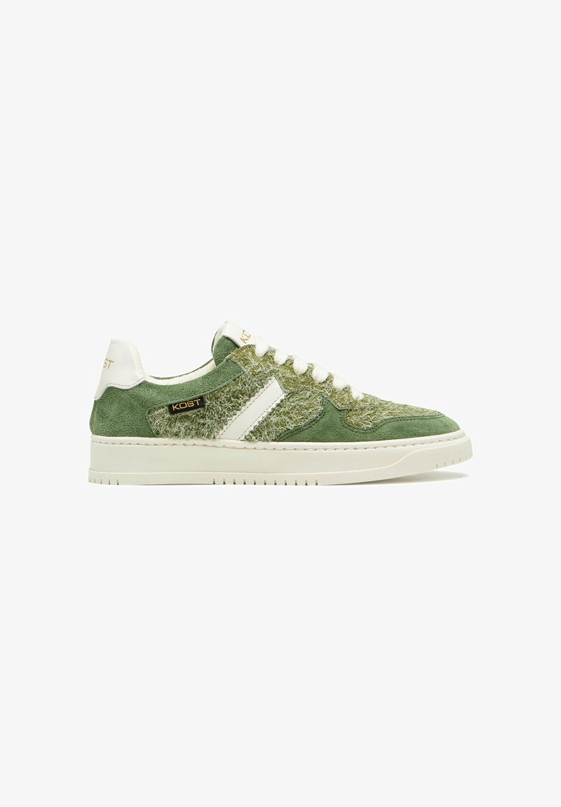 Sneaker en velours vert avec un dessus en tissu texturé, accents blancs, bout rond, semelle plate blanche et détails en logo doré sur le côté.
