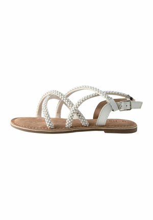Flad åben sandal med tan sål, hvide perlebesatte krydsede remme og en justerbar hvid ankelrem med sølvspænde.