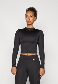 Fekete, hosszú ujjú crop top, kerek nyakkivágással, sima anyagból készült; diszkrét márkalogó található az oldalán, és testhez simuló szabású.