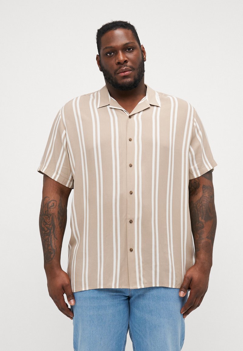 Camisa de botones de manga corta en color beige con rayas verticales blancas, cuello tipo campamento y botones marrones. Hecha de una tela ligera.