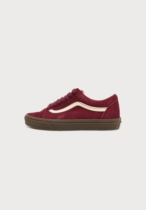 Lage bordeauxrode suède sneaker met crèmekleurige zijstreep, bijpassende bordeauxrode veters en bruine rubberen zool, zijaanzicht op witte achtergrond.