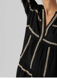 Black dress with a textured fabric, featuring contrasting beige embroidered lines and a v-neckline, with gathered accents at the waist.