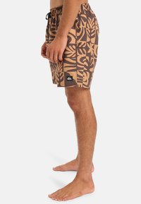 Hnědé plavky s kontrastním béžovým květinovým vzorem, elastickým pasem, nastavitelnou šňůrkou a logem na lemu.