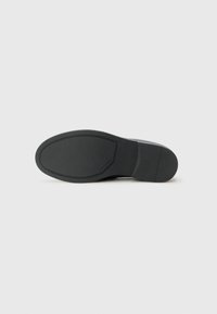 Talpa de pantof din cauciuc negru, cu o suprafață netedă, călcâi ușor curbat și logo-ul mărcii embosat. Design minimalist, plat, fără profil.