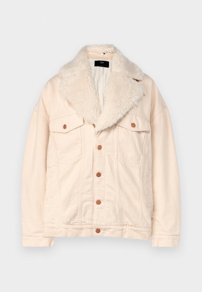 Chaqueta de mezclilla beige con cuello de piel sintética, dos bolsillos en el pecho y botones marrones. La textura es suave, con un corte relajado y un acabado liso.