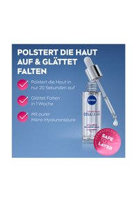 Clear glass serum bottle with a silver dropper cap. Features blue text and a pink badge stating "Safe to Layer." Background is gradient blue.