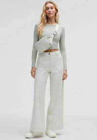 Light gray crop top and high-waisted, wide-leg pants, paired with a small crossbody bag and white sneakers. Smooth fabric, minimal design.