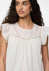 Blusa bianca realizzata in tessuto leggero, con maniche a volant, scollatura tonda e un pannello orizzontale in pizzo decorativo sul petto.