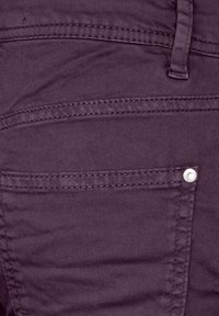 Pantalons en denim violets avec une surface texturée, présentant une poche avant, des coutures contrastées et un accent en bouton argenté.