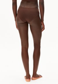 Bruine katoenen bikinislip met een brede tailleband, gladde textuur en een klassieke snit, gezien van achteren, gedragen door een model met blote voeten.