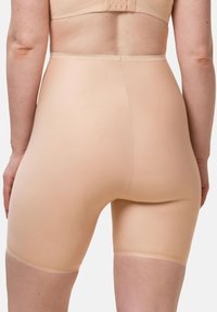 Shorts moldeadores beige de cintura alta hechos de un material liso y elástico, con una longitud hasta la mitad del muslo y construcción sin costuras para mayor comodidad.