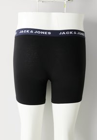 Schwarze Herren Boxershorts mit marineblauem Bund, der mit weißem "JACK & JONES" Branding versehen ist, auf einem weißen Mannequin-Torso.