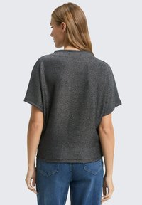 Tmavošedý krátky rukáv top s voľným strihom, vyrobený z textúrovanej, lesklej látky. Má zaoblený výstrih a mierne spustené plecia.