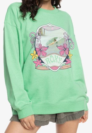 Grön sweatshirt med rund halsringning, med en färgglad surfgrafik omgiven av blommönster. Mjuk bomullstyg med ribbad mudd.