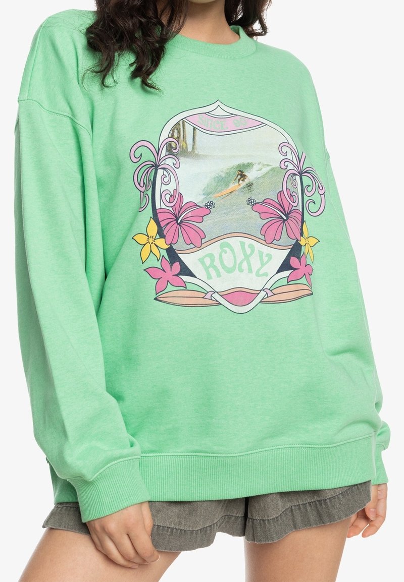 Sudadera verde con escote redondo, que presenta un gráfico de surf colorido enmarcado por diseños florales. Fabricada en suave algodón con puños de canalé.