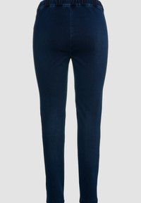 Pantalones de mezclilla azul oscuro con un corte ajustado. La tela tiene una textura suave y una cinturilla elástica para mayor comodidad. Sin detalles de hardware visibles.