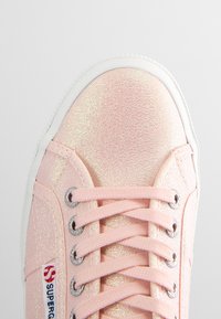 Sneaker in tela glitter rosa con suola in gomma bianca, occhielli in argento e lacci piatti. Caratterizzato da un'etichetta con logo sul lato. Texture liscia e lucida.
