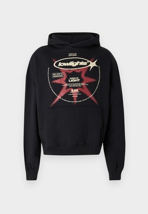 Black hoodie featuring a graphic print in beige and red. Design includes a starburst pattern and text elements. Soft texture and standard fit.
