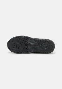 Suela de zapatilla negra con goma texturizada, patrón ondulado y diseño de agarre multidireccional para tracción. Bordes y curvas suaves.