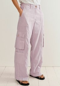 Pantalon cargo violet clair à coupe ample, doté de multiples poches, d'une fermeture à boutons et d'un design décontracté. Tissu en coton texturé.
