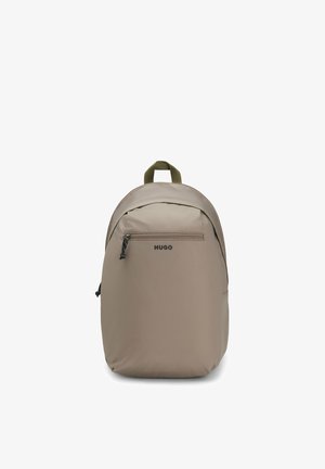 Beżowy plecak Hugo z przednią kieszenią na zamek, oliwkowozielonym górnym uchwytem i czarnymi suwakami, przedstawiony na białym tle.