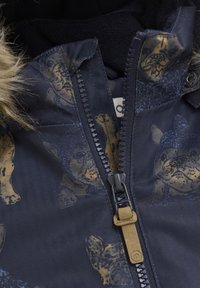 Marineblå jakke med dyreprint i guld, hættestruktur i herringbone, lynlås lukning og faux fur kant på hætten.