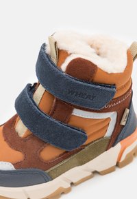 Brązowe i granatowe buty trekkingowe z dwiema rzepami, wyściełanym kołnierzem i mieszanką materiałów, w tym zamszu i syntetyku, z fakturowaną podeszwą.