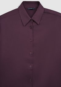 Chemise col maroon en tissu lisse ; dotée de six boutons et d'une coupe classique ; étiquette "CALLIOPE" visible sous le col.