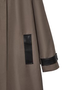 Cappotto cappuccio marrone realizzato in un tessuto morbido, con dettagli in pelle nera su tasche e polsini, e una silhouette strutturata.
